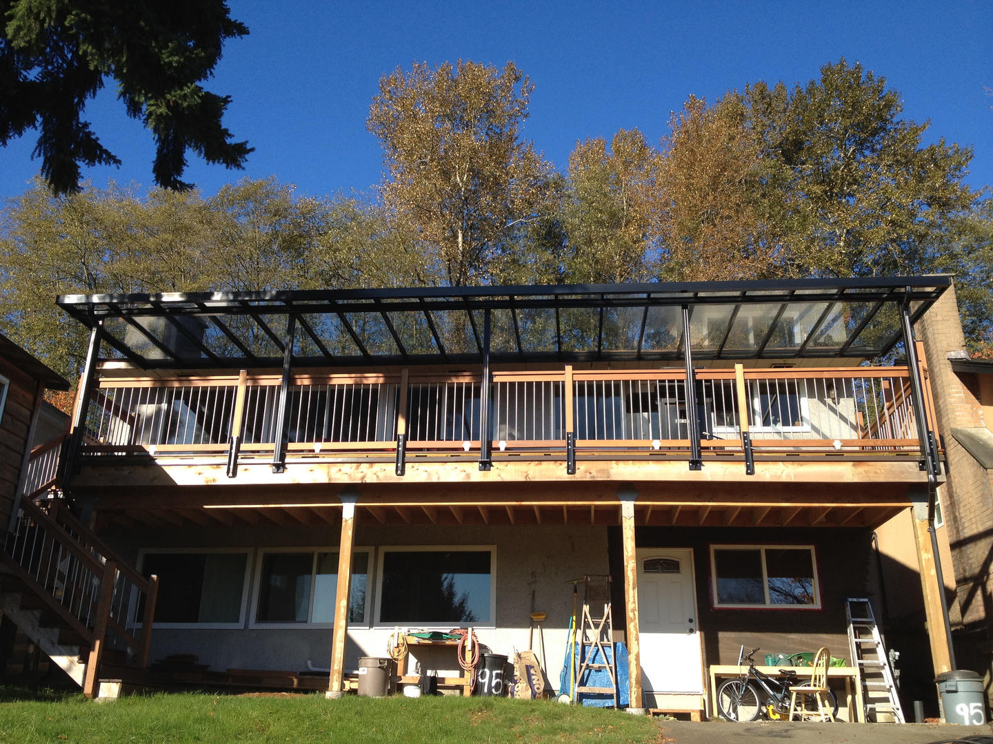A black patio cover with glass paneling on a wide second floor patio