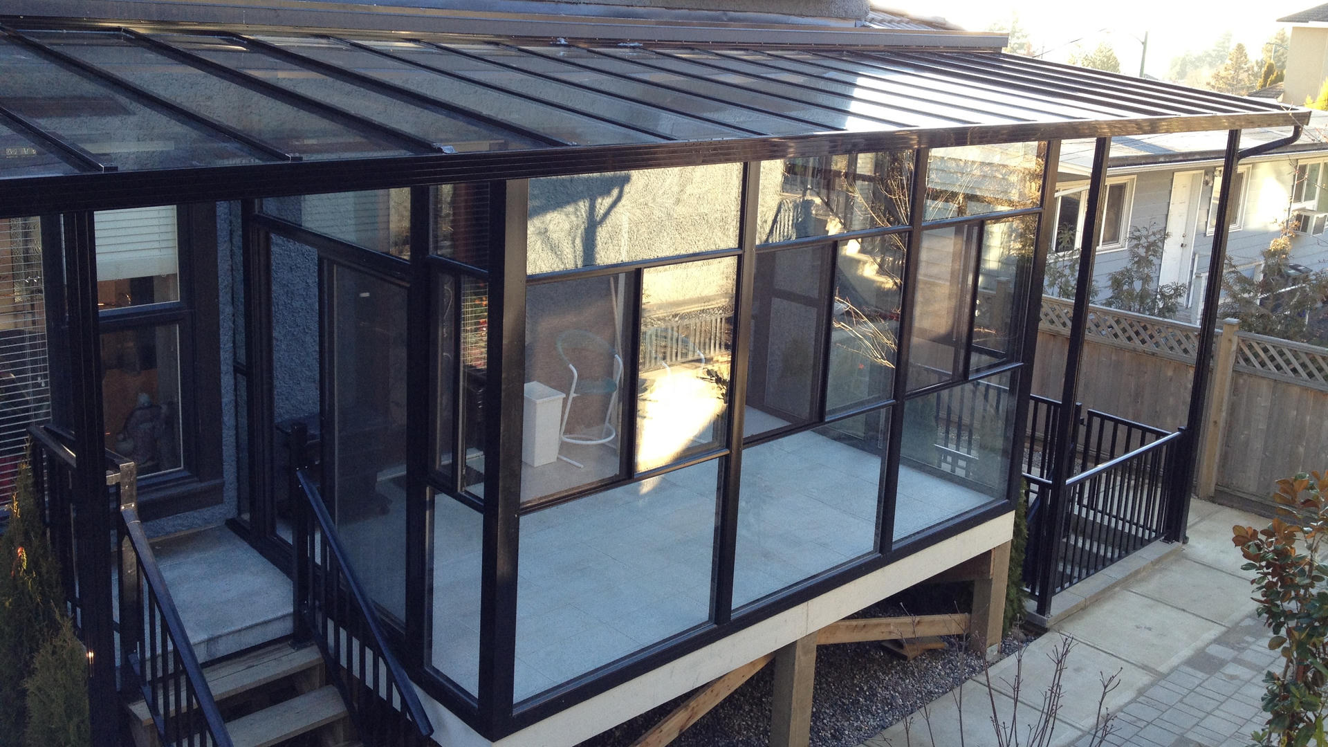 Glass sunroom with black aluminum structure and matching railings